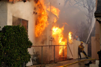 A firefighter sprays water on a house to protect it from the Eaton Fire in the Altadena neighborhood on Jan. 8, 2025 in Pasadena, Calif. Credit: Nick Ut/Getty Images