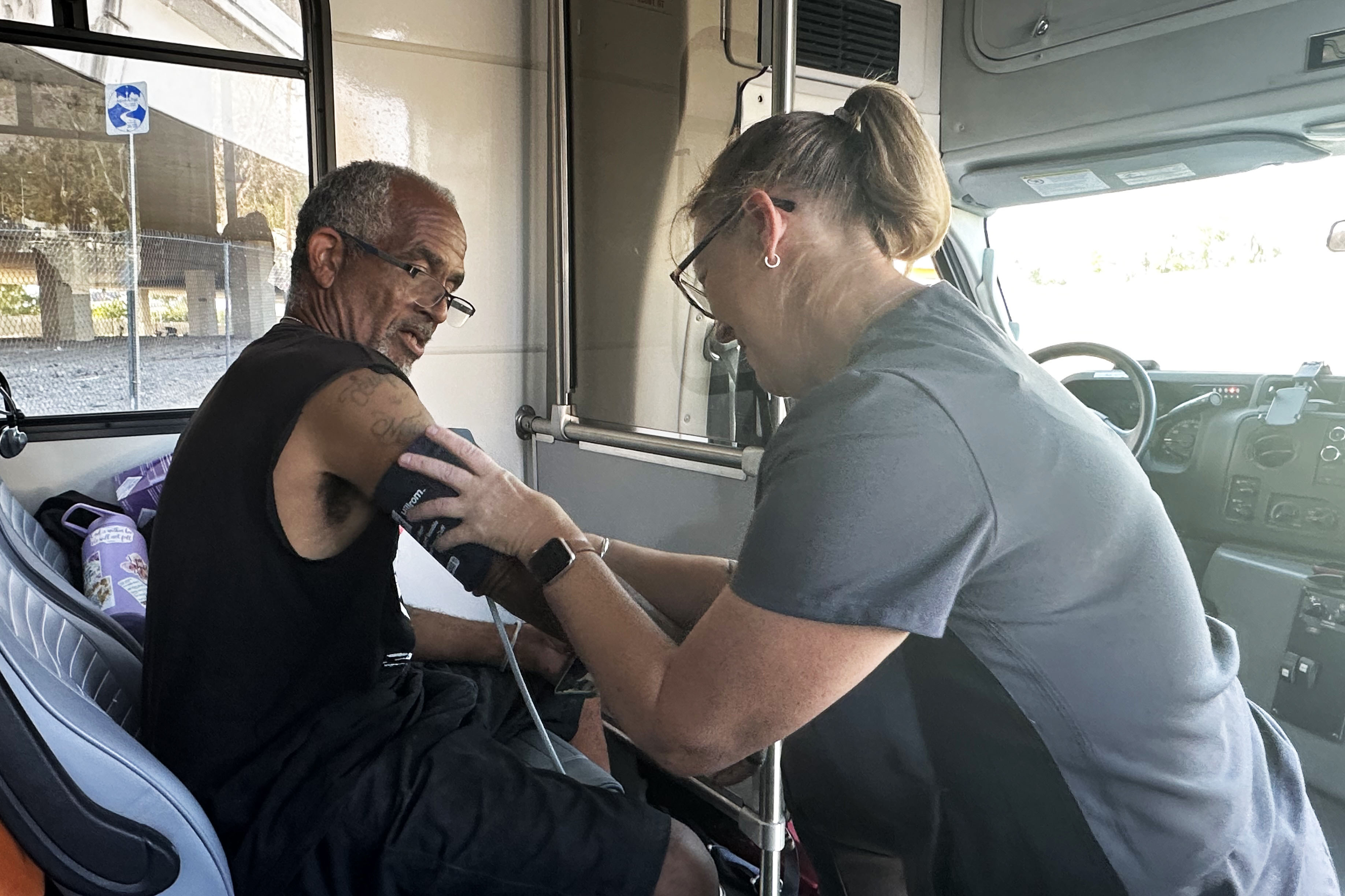 A photo showing John Harris having his blood pressure checked by a woman in a mobile clinic.