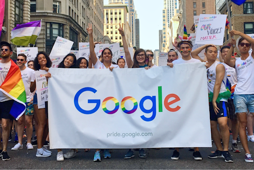 Googlers holding up a banner and pride flags, marching together at a Pride parade