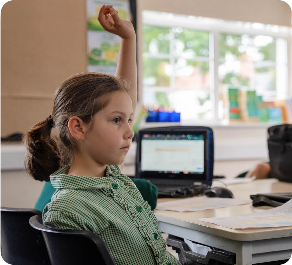 A young girl raising her hand in class.