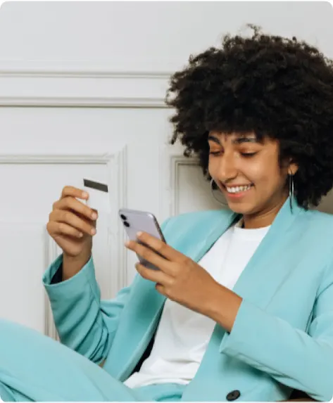 Una mujer joven vestida con un traje realiza una compra desde el dispositivo móvil.