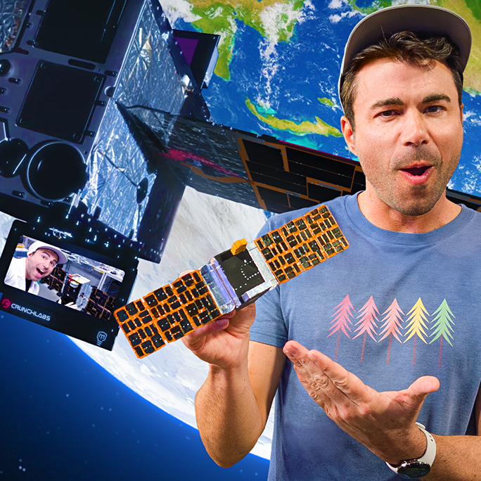 Mark Rober poses with a satellite with Earth in the background.