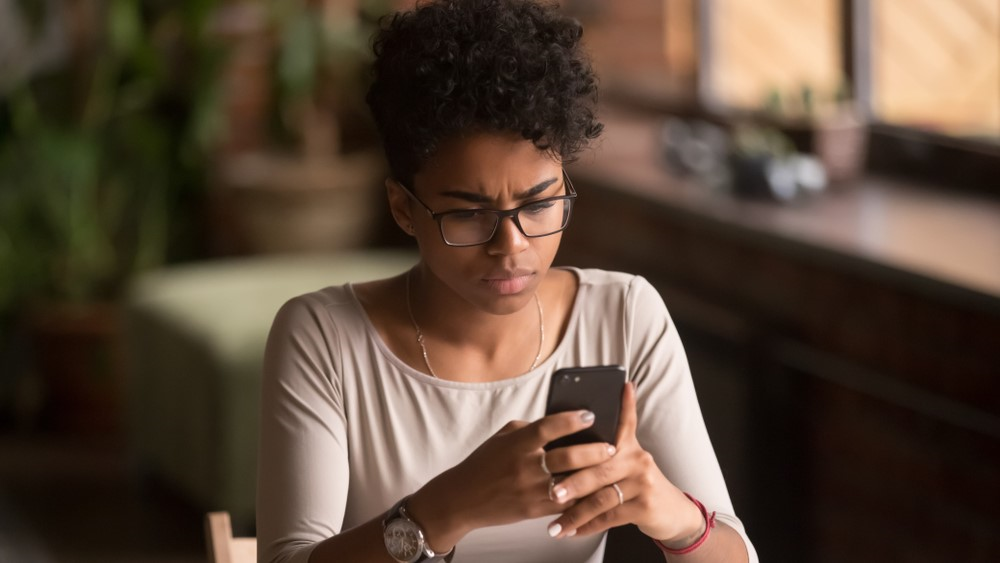 A person looking at her phone with a confused look