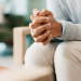 A person's folded hands as they sit in a session with their therapist