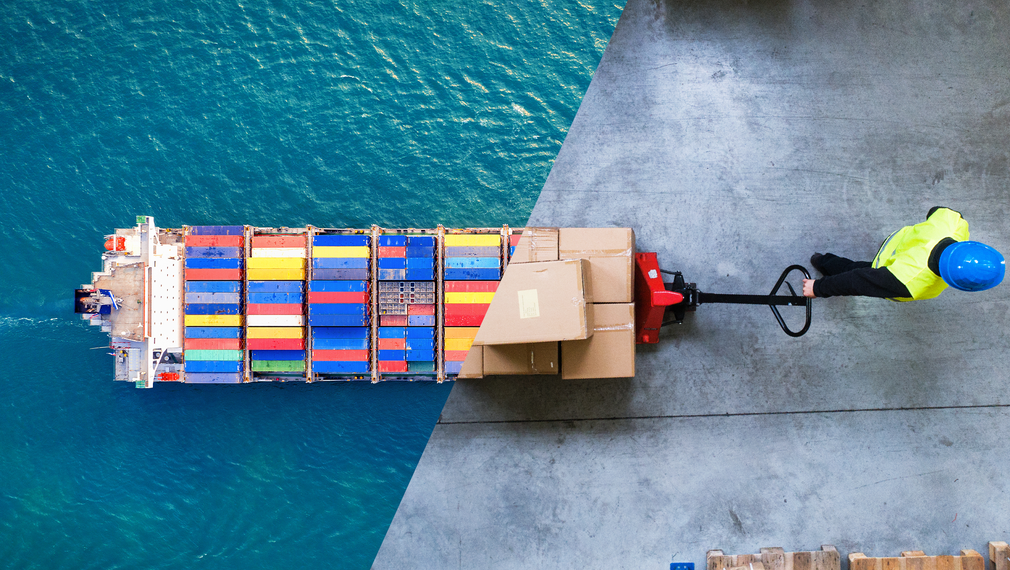 a man is pushing a pallet truck towards a large ship