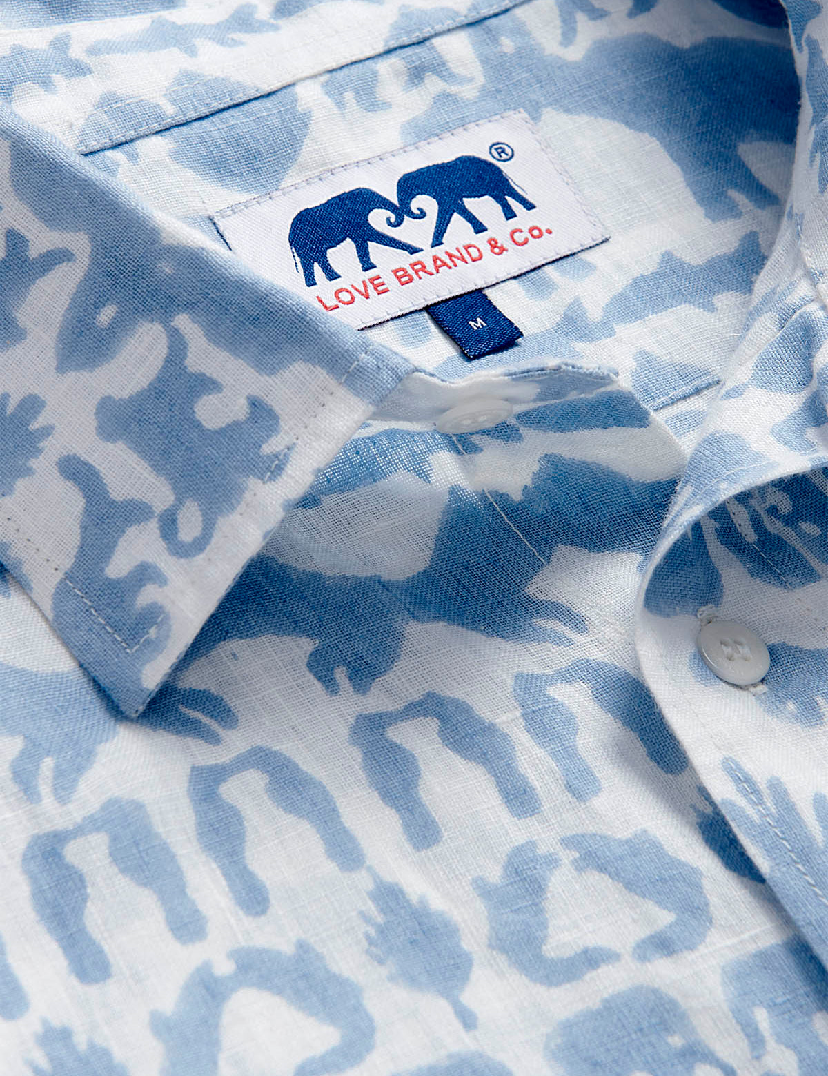 Close-up of unisex linen long sleeve shirt featuring 'Coexist' print in sky blue with various Indian jungle animals. The collar showcases the Love Brand & Co. label.