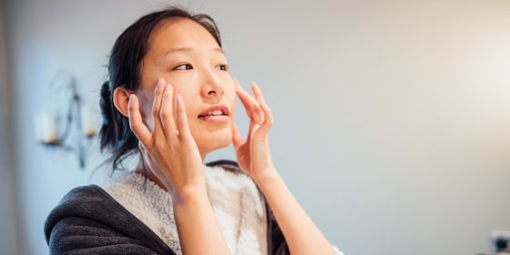 Woman washing her face in front of the mirror