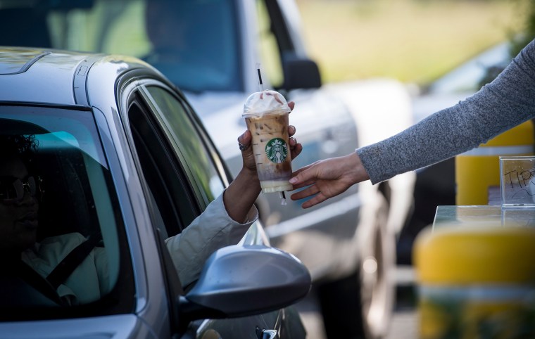 A barista passes a drink order to a customer at a Starbucks drive-thru in Rodeo, Calif.,