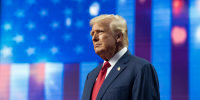 Donald Trump stands in front of an American flag backdrop