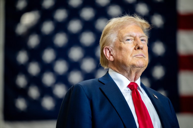 Donald Trump on stage in front of an American flag backdrop