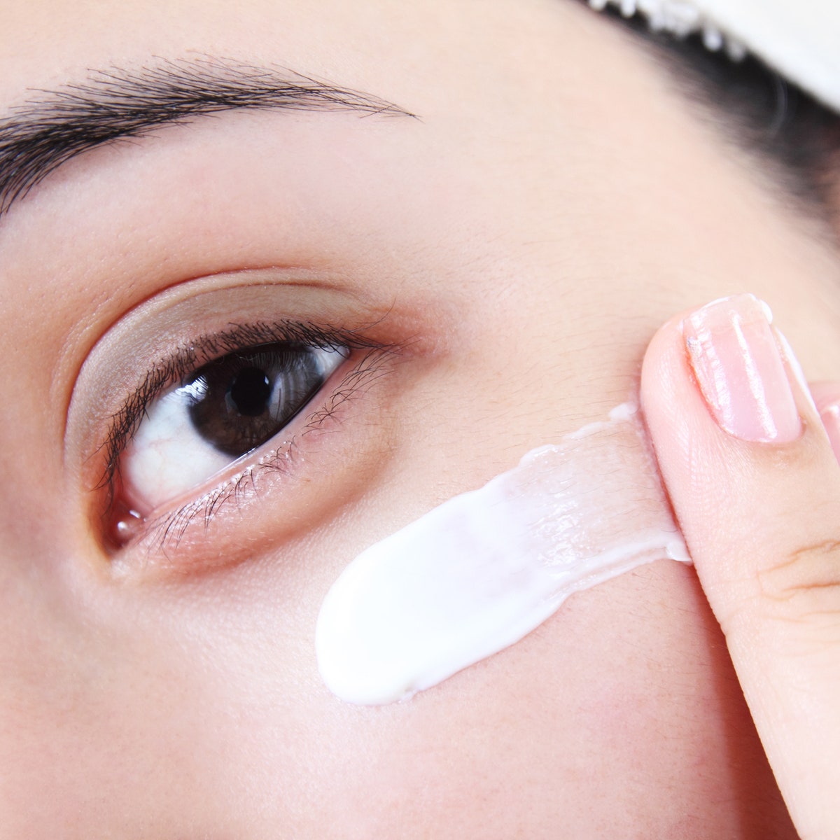 Closeup image of woman applying eye cream