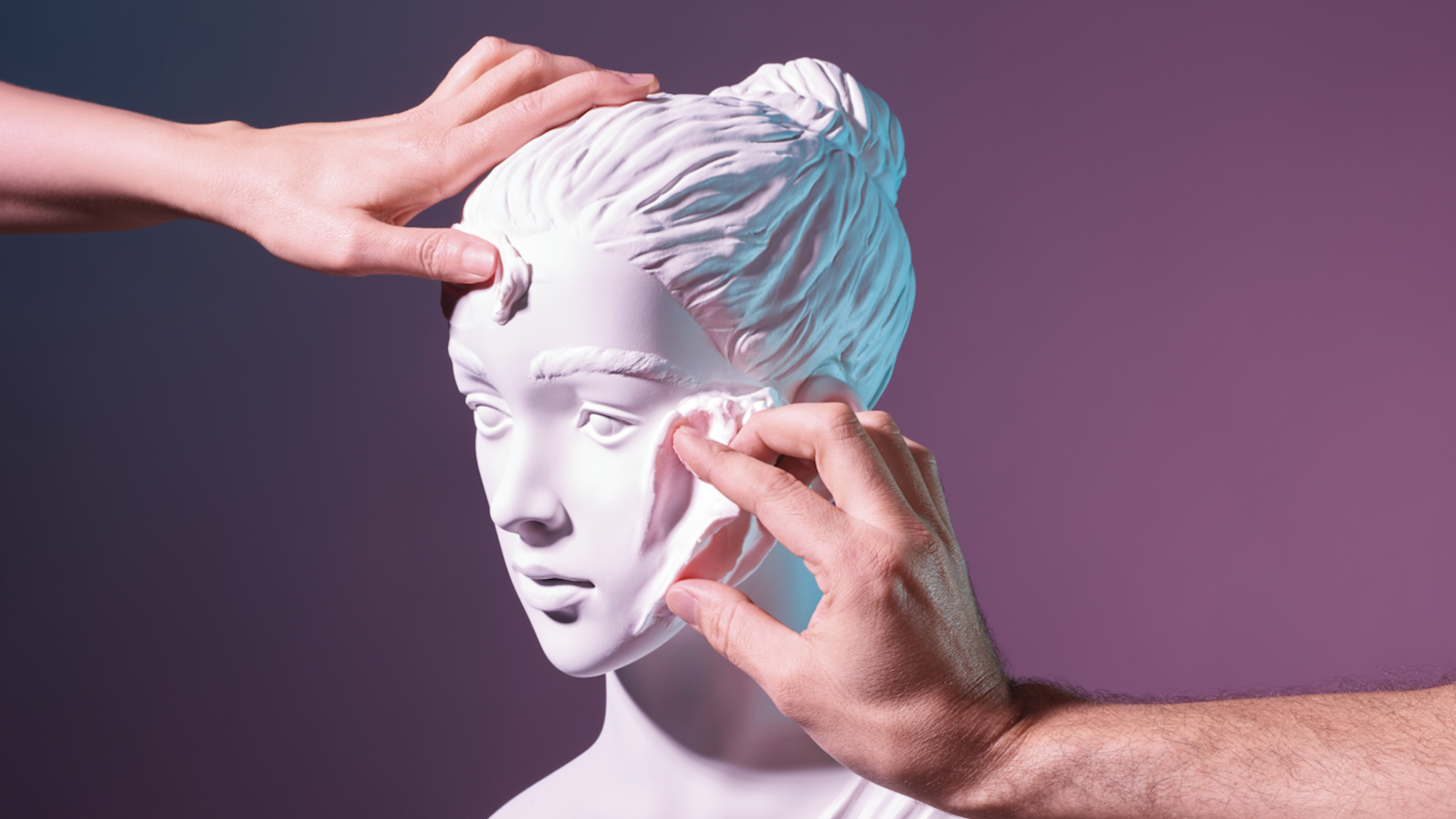 two hands sculpting a bust