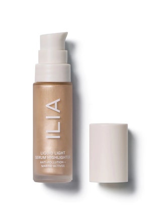 Ilia Beauty Liquid Light Serum Highlighter jar of pale gold liquid highlighter with dispenser pump and cap on white...