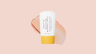 A white tube of the Beauty Pie Traceless SPF 30 Sunscreen  Primer on a light pink background