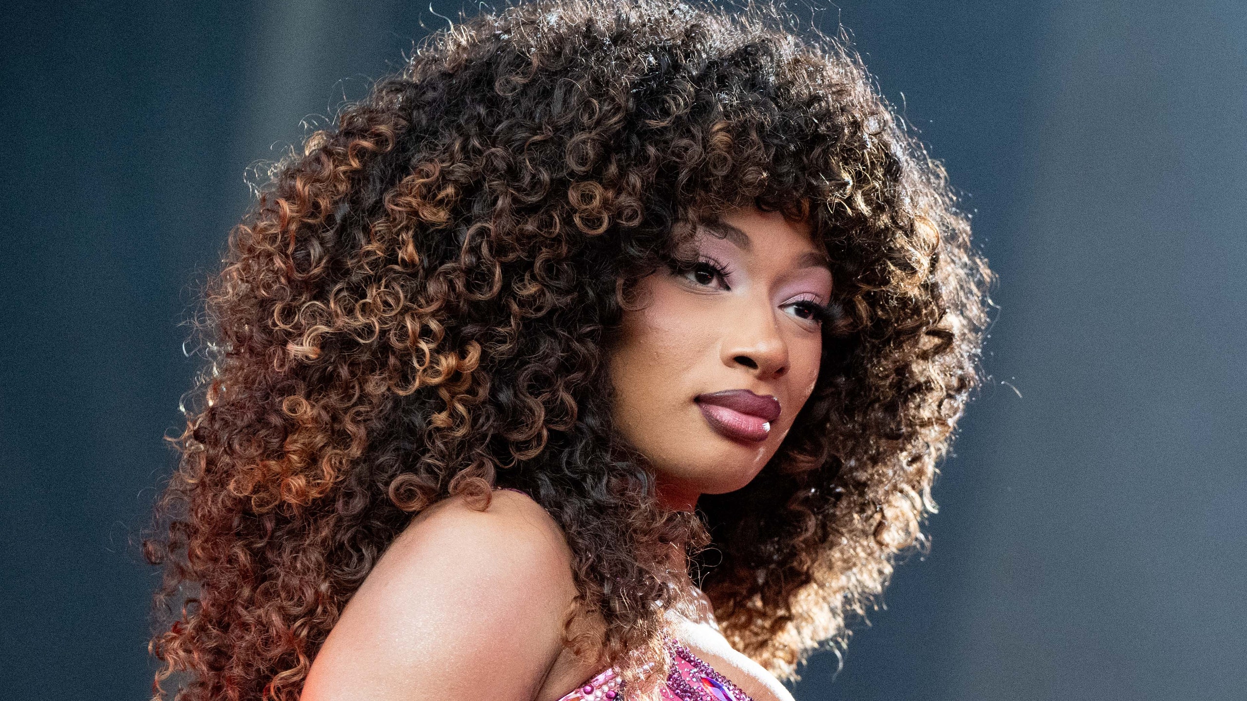 Megan Thee Stallion performs onstage wearing a purple outfit and big curls.