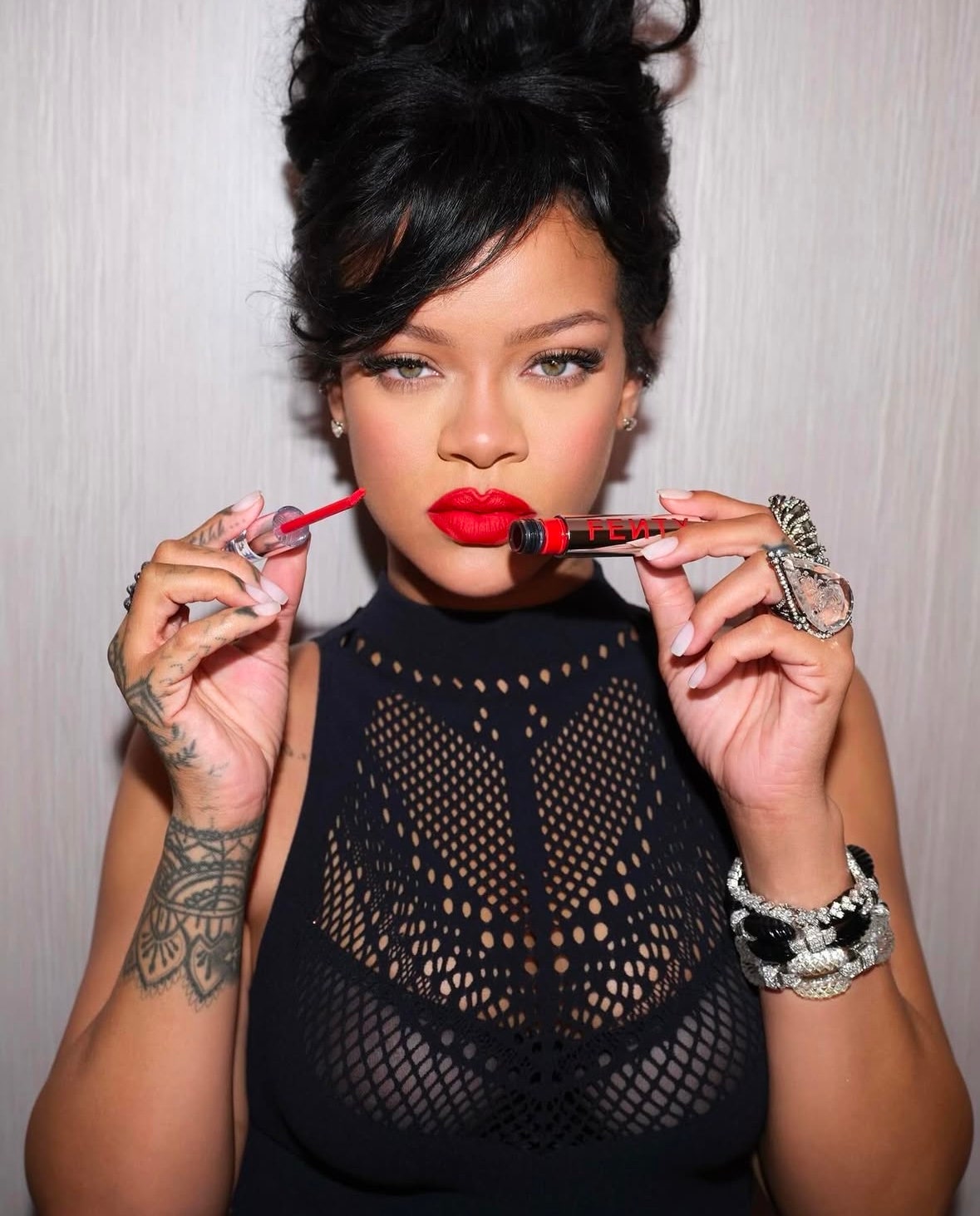 Rihanna holding up red liquid lipstick