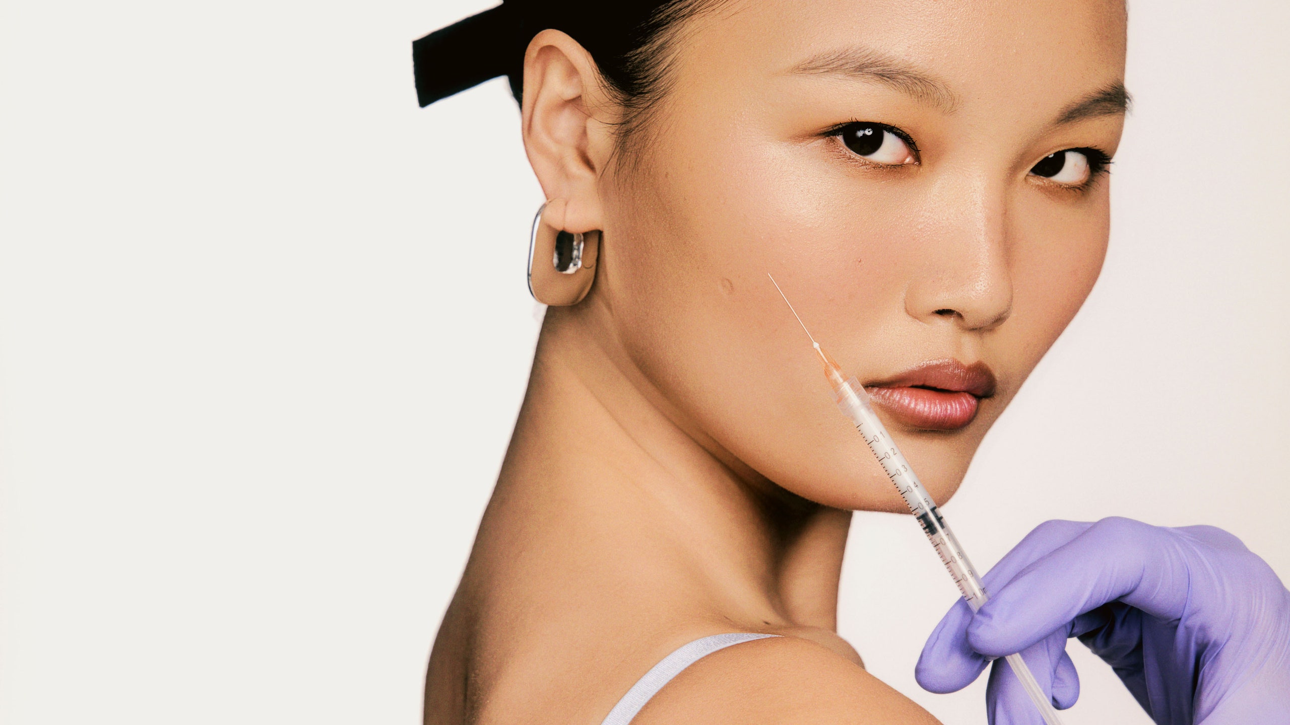 image of woman looking at the camera while a syringe is held up close to her face