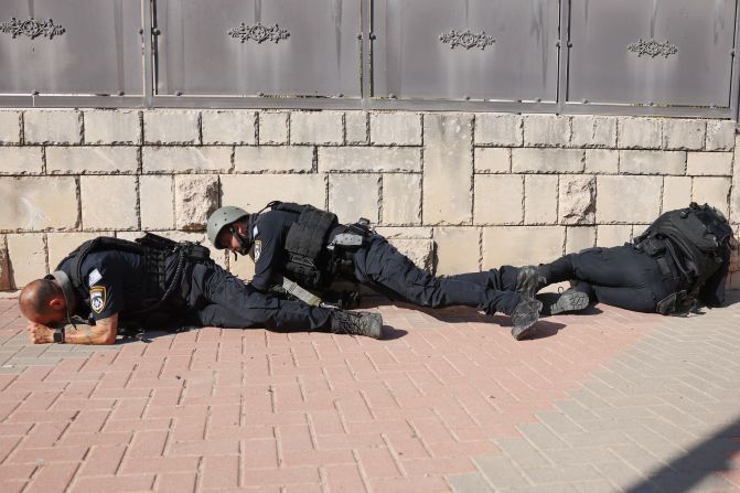 Israeli police take cover in Ashkelon as sirens wail while rockets are fired from Gaza into Israel on October 7.