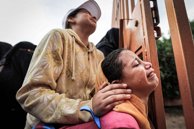 People mourn as they stand behind a metal fence before the burial of victims killed in an Israeli bombardment in Khan Younis, Gaza, on Tuesday, November 14.