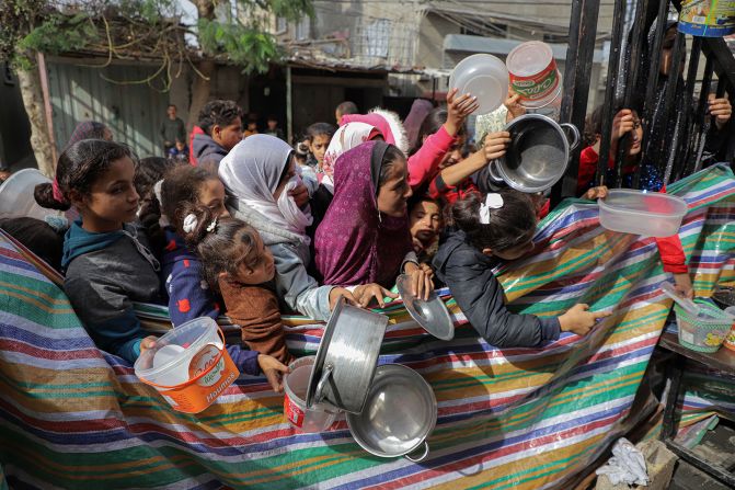 Palestinians clutching empty containers wait for food relief in Rafah, Gaza, on Sunday, November 19.