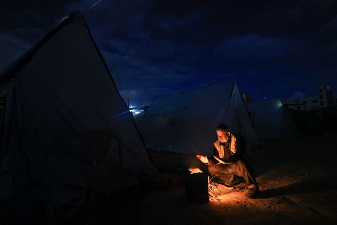 A displaced Palestinian man sits by tents sheltering people near the border between Israel and southern Gaza, in Khan Younis on November 27.