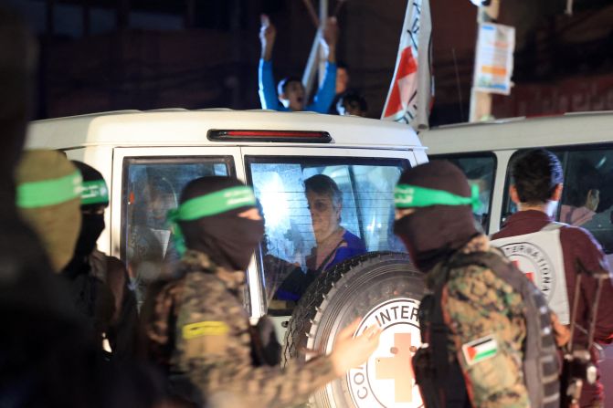 Hamas and Islamic Jihad fighters stand guard as Red Cross vehicles transport released hostages towards the Rafah border crossing with Egypt, in southern Gaza, on November 28.