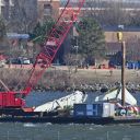 US Navy recovery teams lift the back wing section of an American Airliners plane from the Potomac in Arlington, Virginia on February 4, 2025. Operations to salvage the wreckage from a deadly collision between a US Army helicopter and a passenger jet continued as rescuers said 55 victims had so far been identified. Dozens of victims have been pulled from the icy Potomac River, and rescuers voiced confidence that those remaining would be retrieved in the massive operation to recover the plane that collided in midair with a Black Hawk military helicopter. (Photo by ROBERTO SCHMIDT / AFP) (Photo by ROBERTO SCHMIDT/AFP via Getty Images)