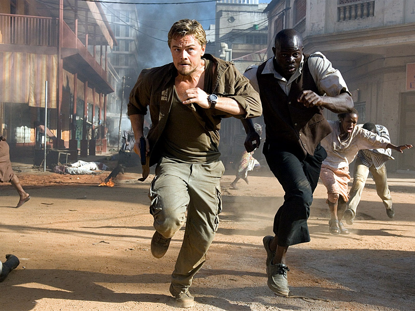 Image may contain Leonardo DiCaprio Djimon Hounsou Chasing Person Wristwatch Adult Clothing Footwear Shoe and Gun