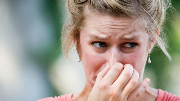 A woman holds her nose. 