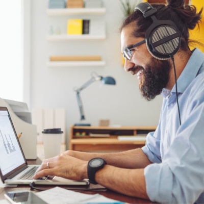 Employee with headphones on sitting at a desk working on a laptop.