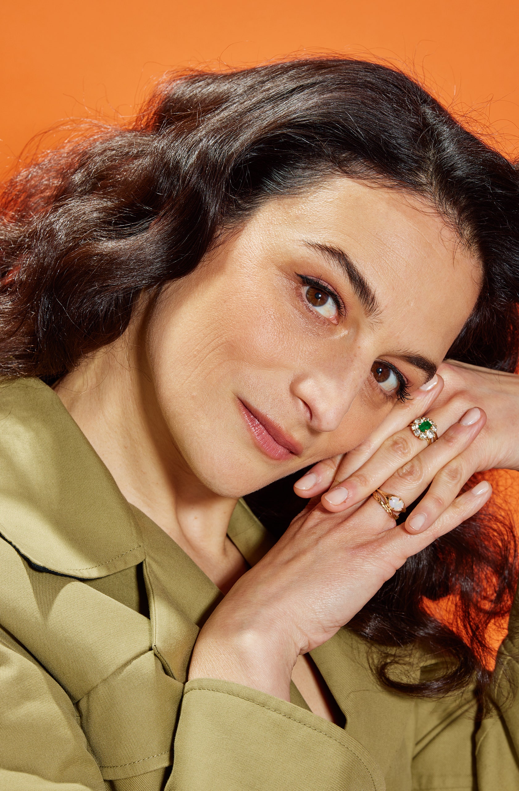 A portrait of the actor and comedian Jenny Slate with an orange background behind her.