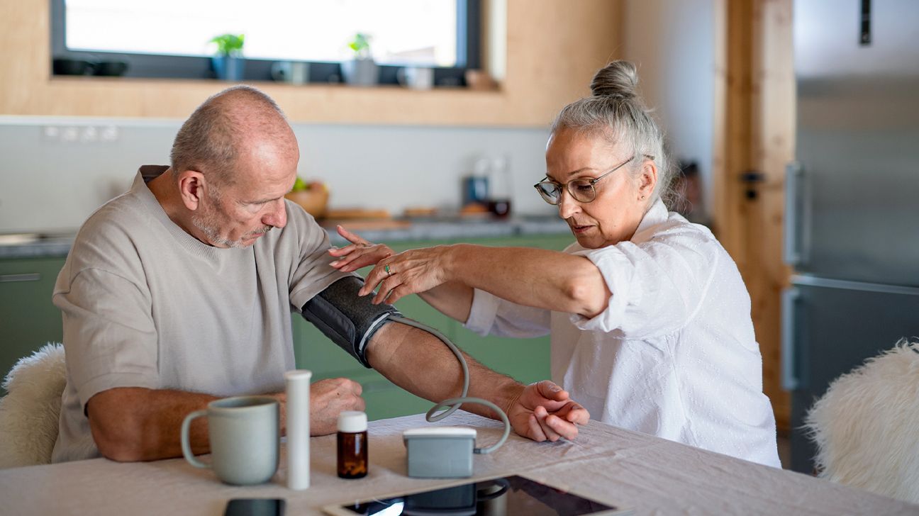 older person with renal hypertension taking their blood pressure at home