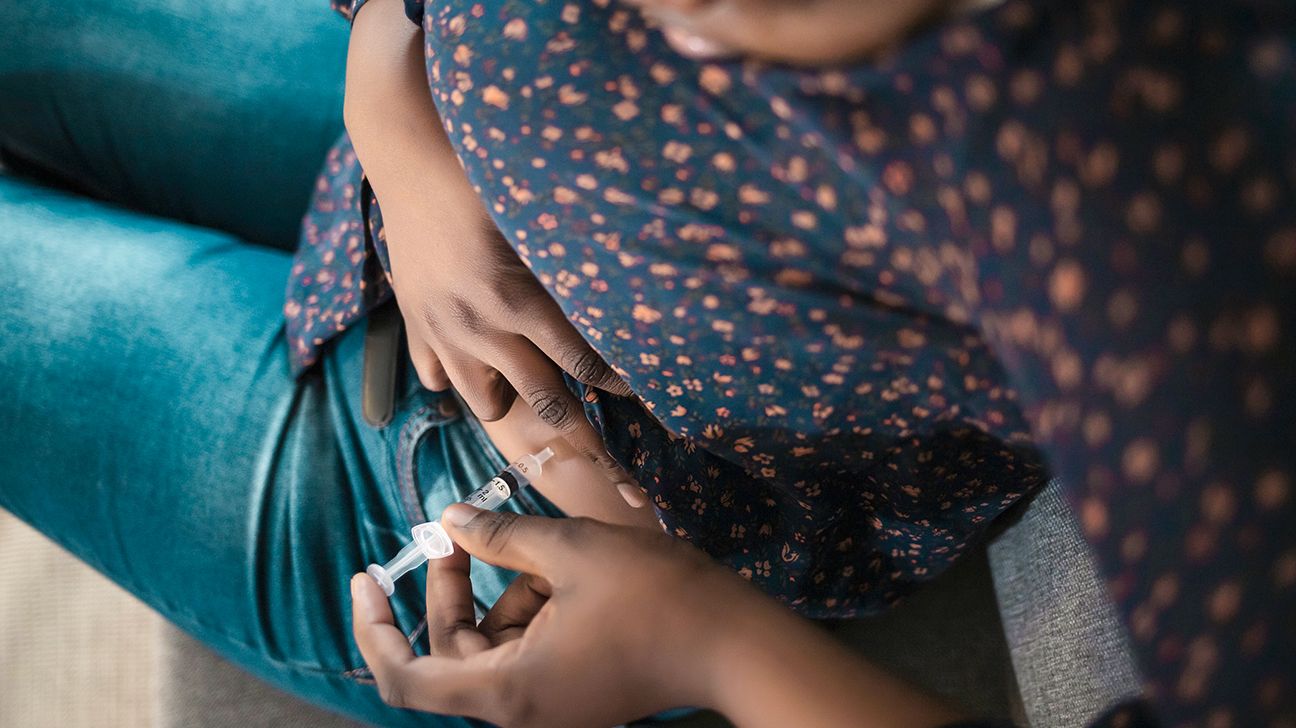 Person using a syringe to inject insulin into their abdomen.