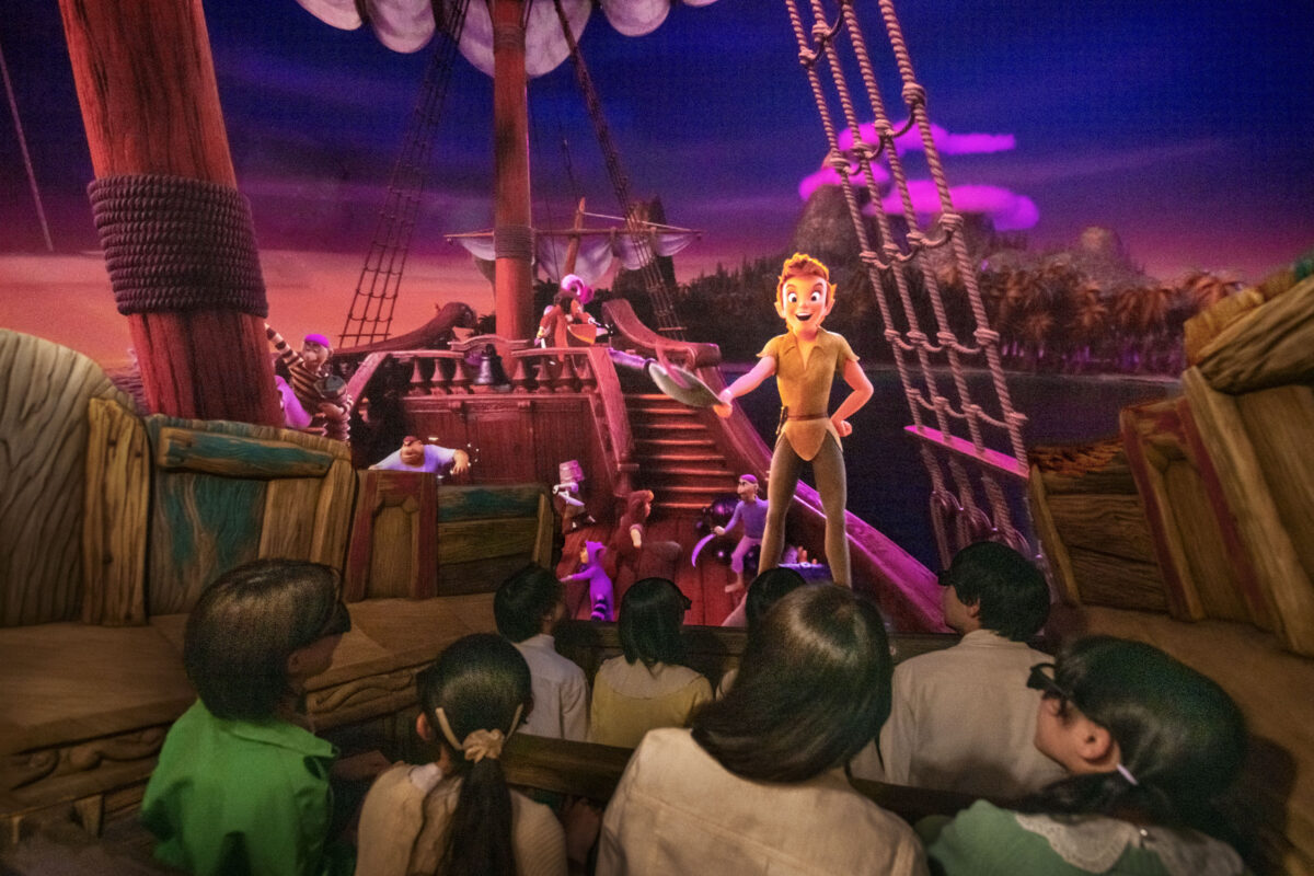 Children watching a peter pan animatronic character on a pirate ship set in a themed attraction.