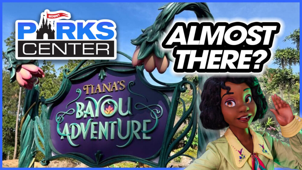 Image showing a decorative sign reading "Tiana's Bayou Adventure" with the text "ALMOST THERE?" above it. A character dressed in a green outfit is smiling and waving in the bottom right corner, capturing the joyous spirit of ParksCenter.