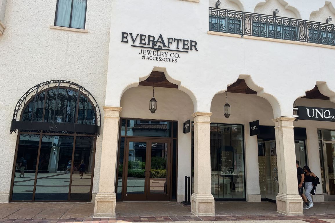 The elegant storefront of Ever After Jewelry Co. & Accessories is nestled in a charming white building, featuring arched doorways and classic black lanterns.