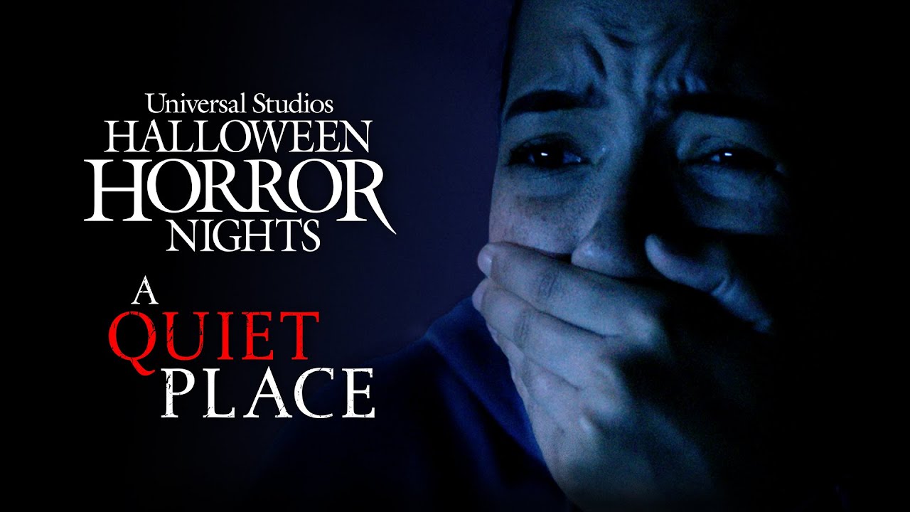 Close-up of a person covering their mouth in fear next to the text "Universal Studios Halloween Horror Nights: A Quiet Place" against a dark, eerie background.