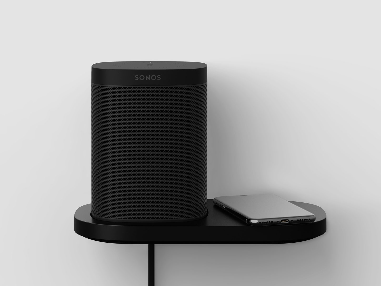 Tall Sonos Shelf speaker sitting on a shelf with a phone.