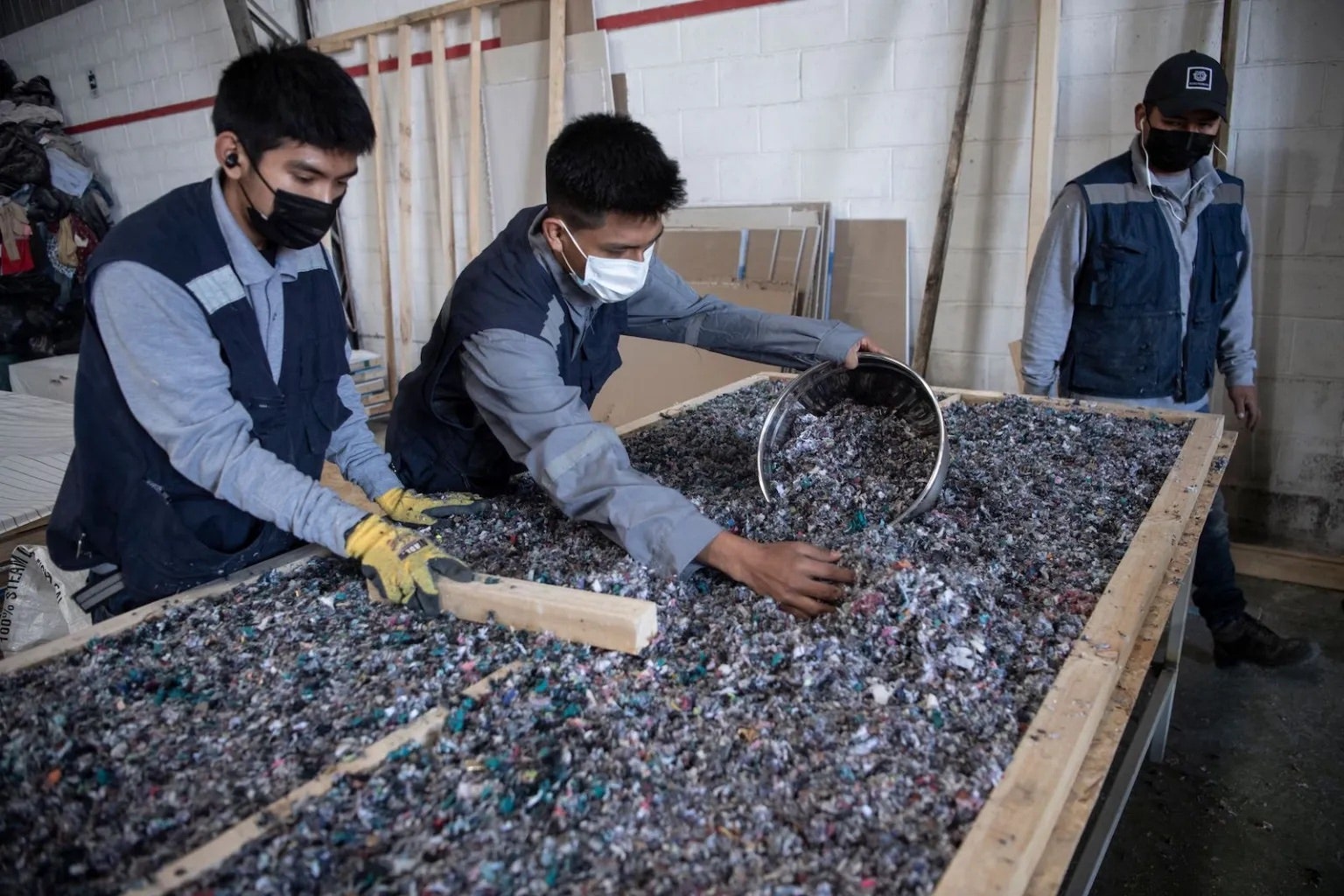 men working with discarded clothing items