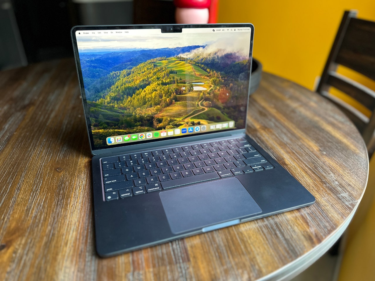 MacBook Air M3 open to display mountain background sitting on wooden table