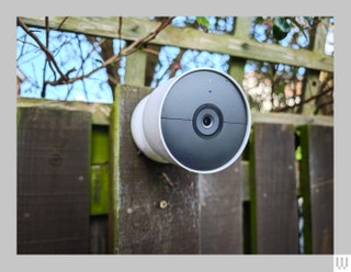 White and grey coneshaped security camera attached to a wooden fence