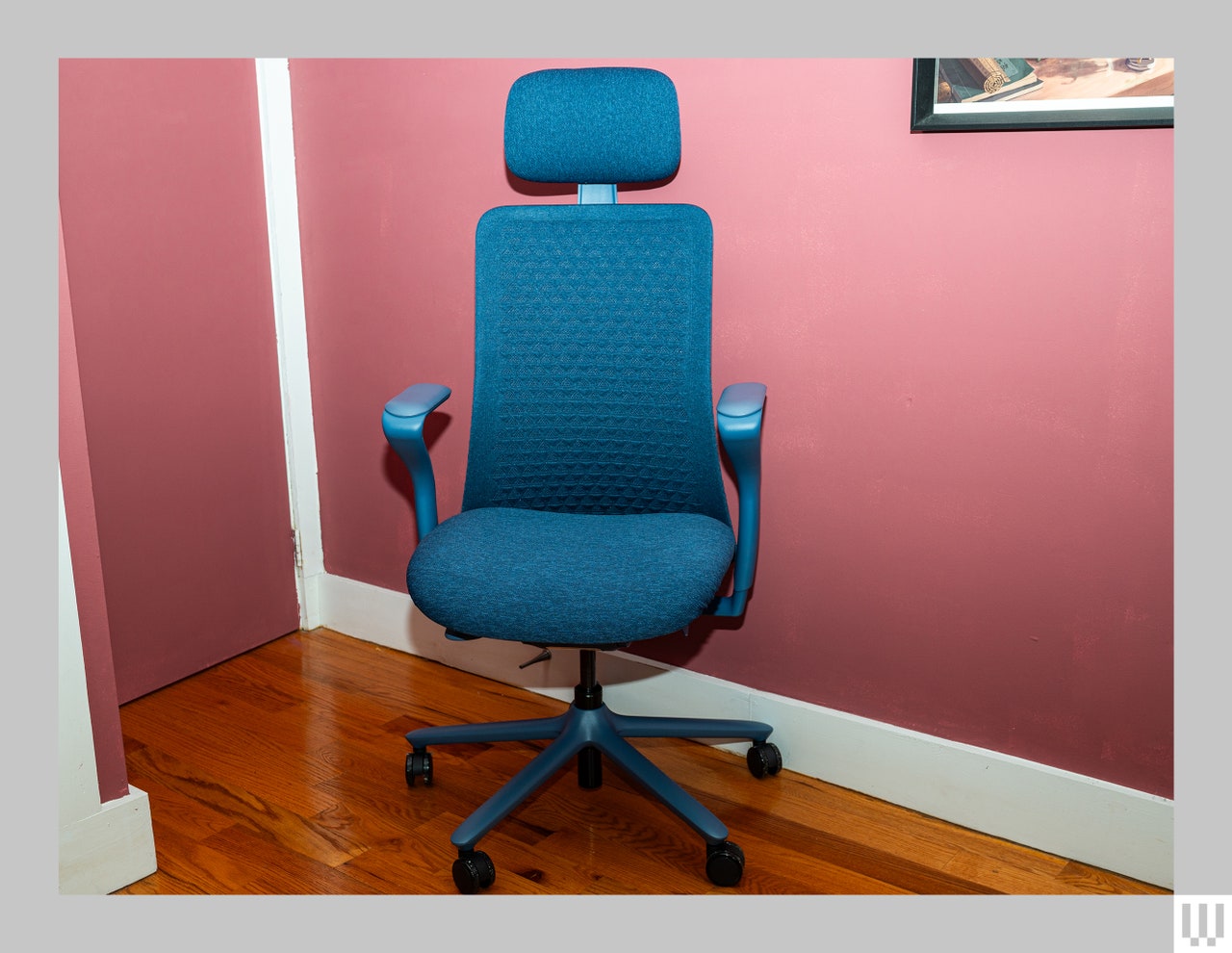 Front view of blue office chair in a room soft pink walls and hardwood floors