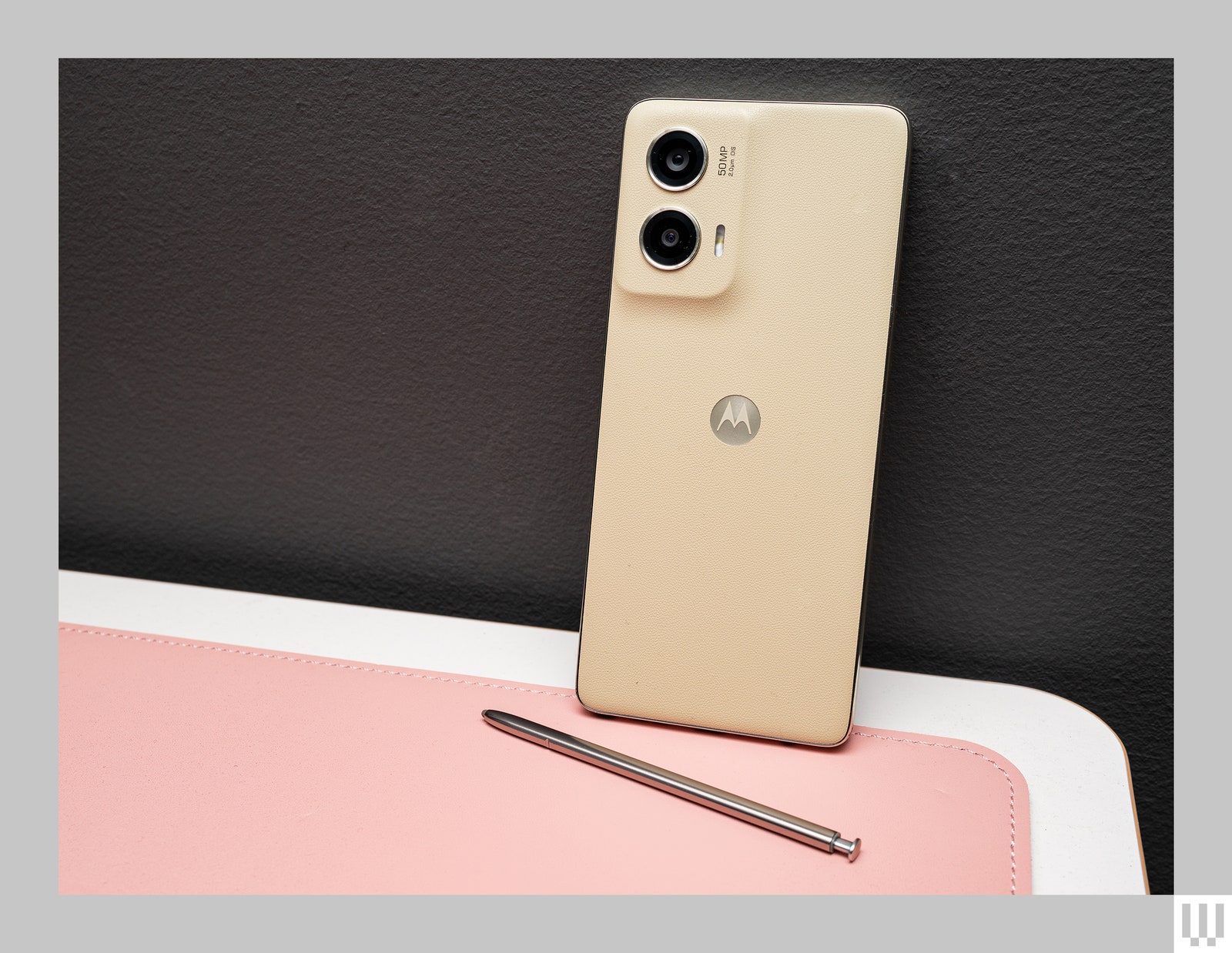 Beige narrow rectangular mobile phone leaning up against a wall with the backside facing outwards to show the 2 cameras...