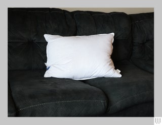 Fluffy white rectangular pillow on dark couch