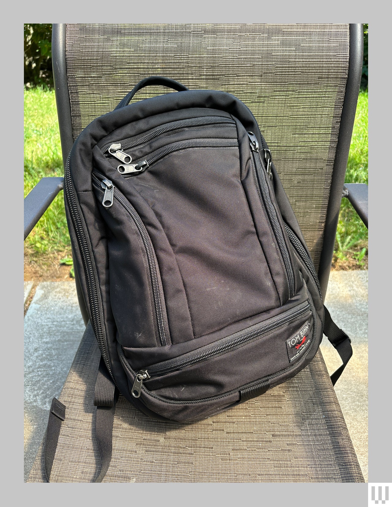 Black backpack with zippers, propped up on mesh lawn chair