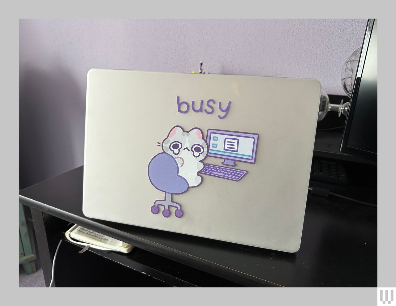 Laptop cover showing a little crying character working in an office chair in front of a computer with the word "busy" 