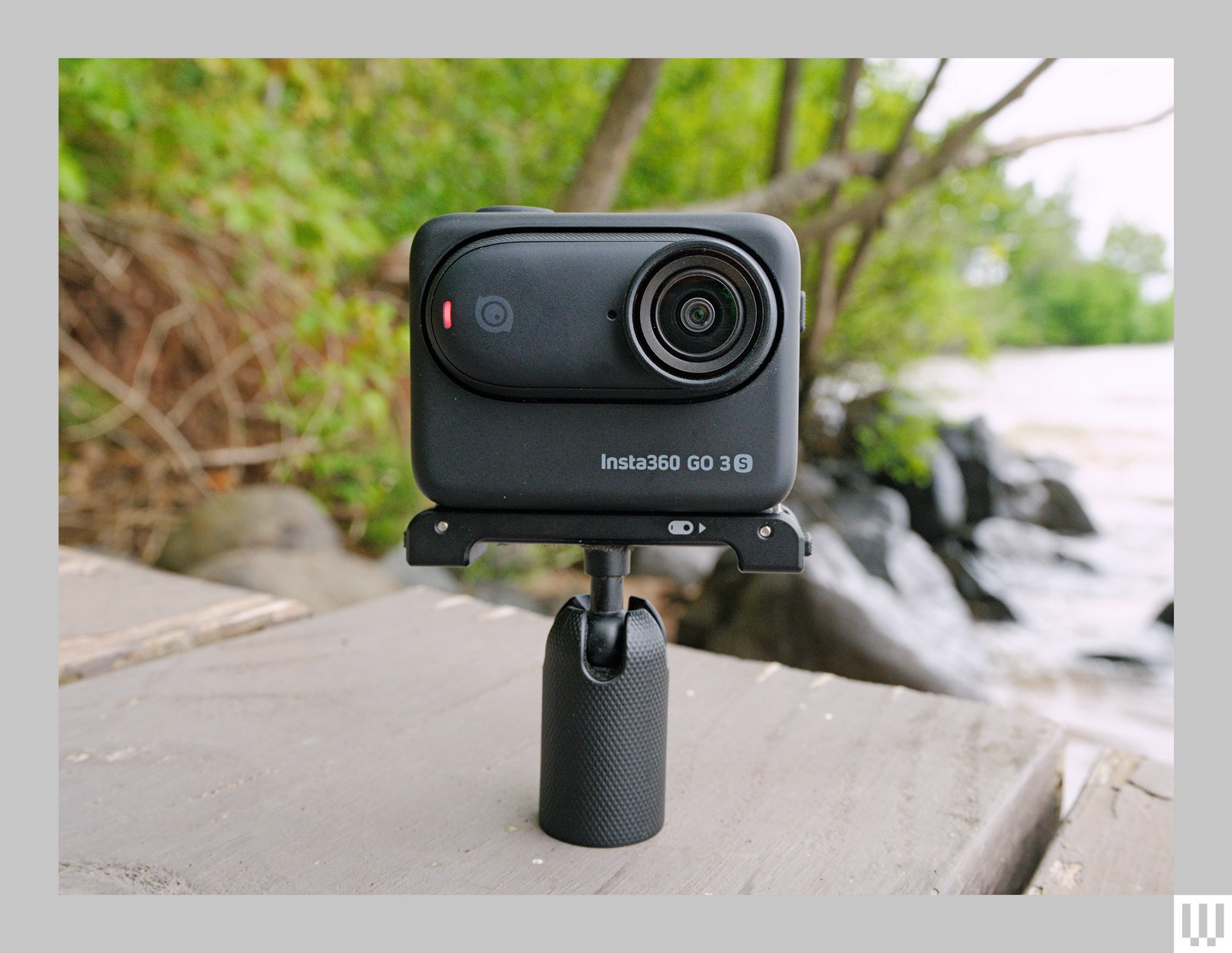 Small simple camera on a handle sitting on a wooden dock beside water