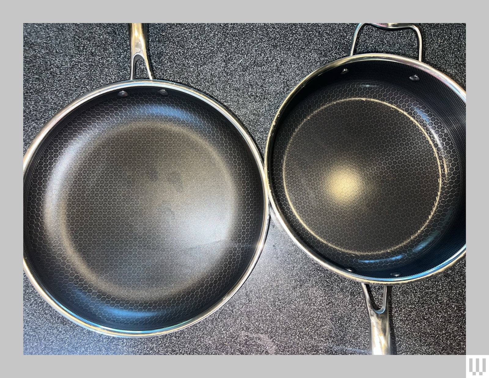 Two silver cookware pans side by side on a black speckled countertop