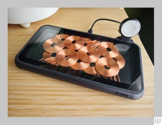 Mobile phone resting on a small charging pad on the edge of a table