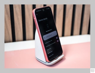 White wireless charger phone stand propping up a bright pink mobile phone